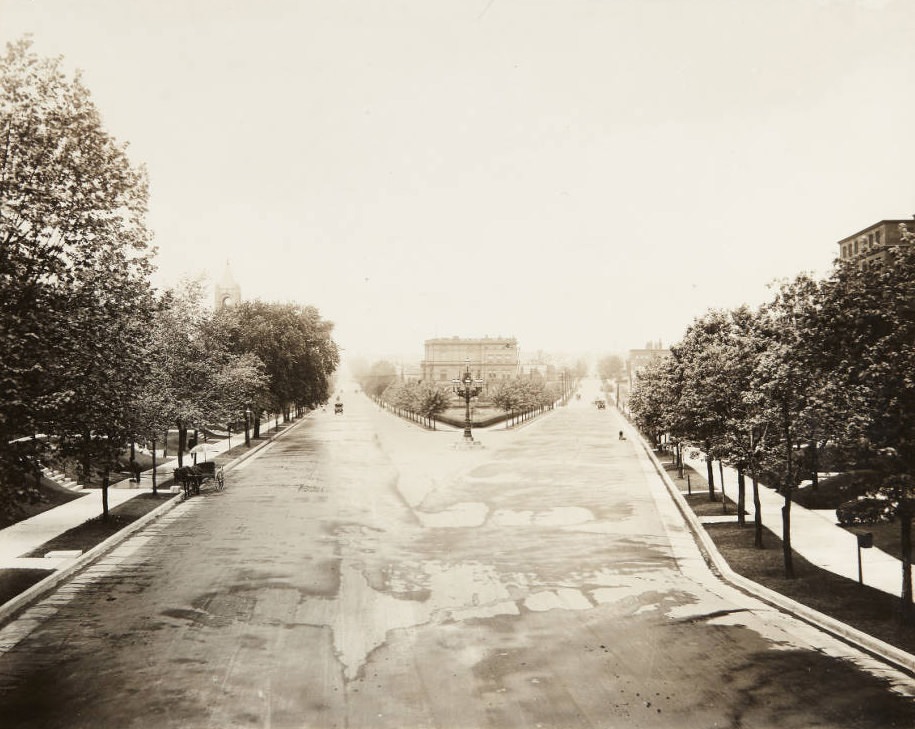 Looking west on McPherson Avenue where it ends at Lindell Blvd. near the northern edge of the St. Louis University campus with a man cleaning the sidewalk on the south side of the street, 1920.