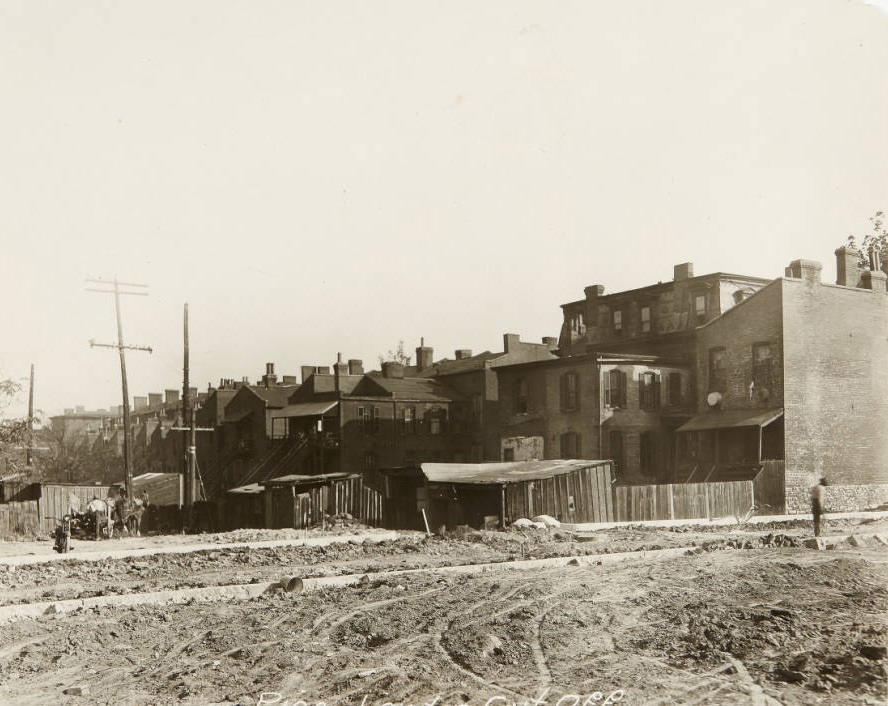 Open lot in front of a row of houses in 1920. A workman with a team of horses and a motorcycle is on the left side of the photo. Written on the front: Pine - Lawton Cut Off.
