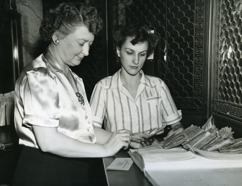 Teller at Mercantile Commerce Bank and Trust Company showing a new employee how to sort canceled checks, 1943.