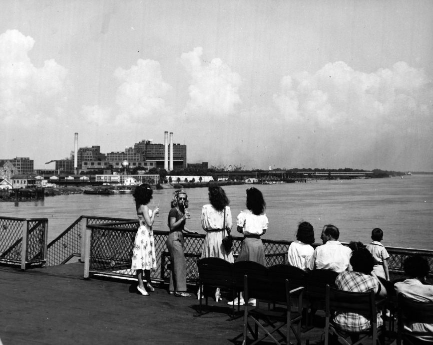 Passengers overlook the Mississippi River as they visit the top deck of the President steamboat.
