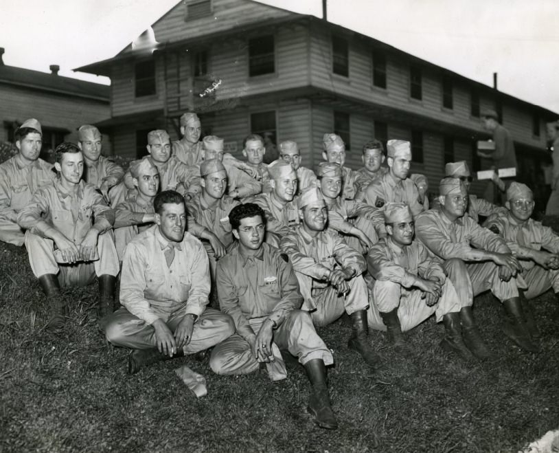 Blackhawks veterans sit on the grass as they wait for physical examinations as preliminaries to furloughs, 1945