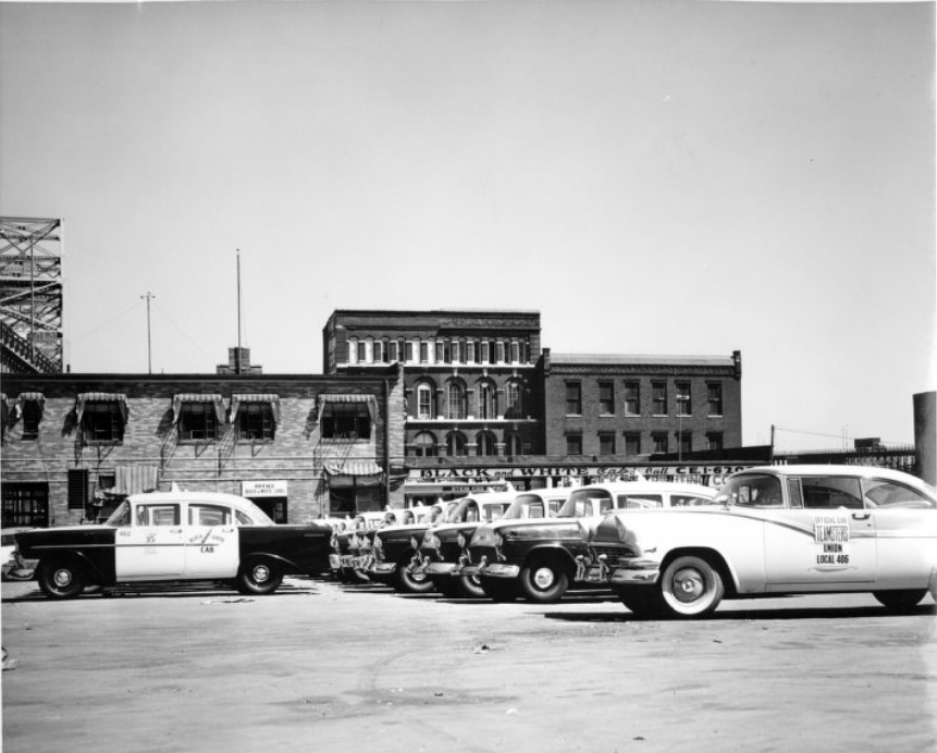 Rows of taxicabs parked outside the Black and White Cab company, 1950