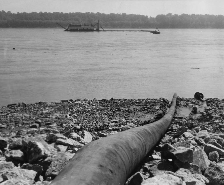 Building a defense against itself, the Mississippi sends sand and silt from a dredge far out in the river through a submerged pipe and up over the bank to the location of a new earthen levee, 1959