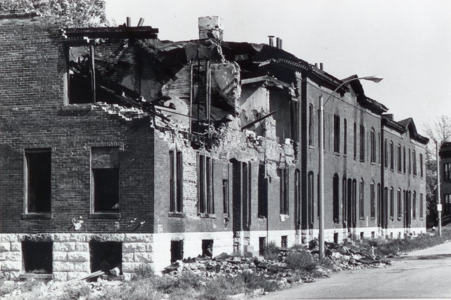 A building deteriorates as the roof begins to fall apart and the inside of the building's structure can be seen, 1974