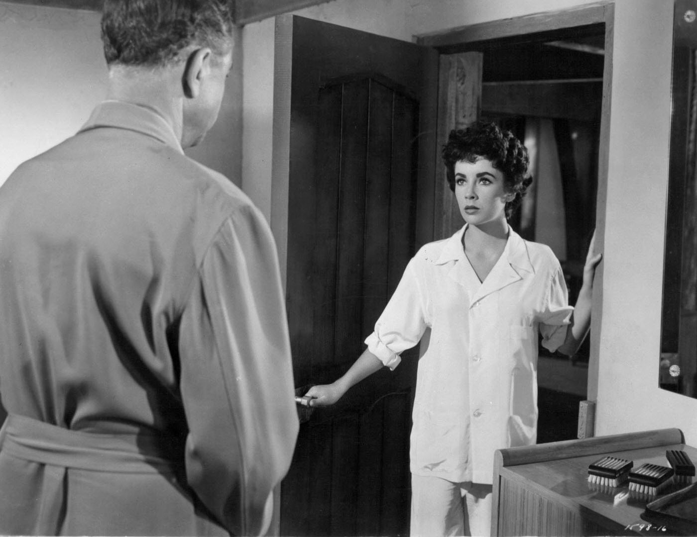 William Powell and Elizabeth Taylor in pajamas by an open door in a scene from 'Girl Who Had Everything' (1953).