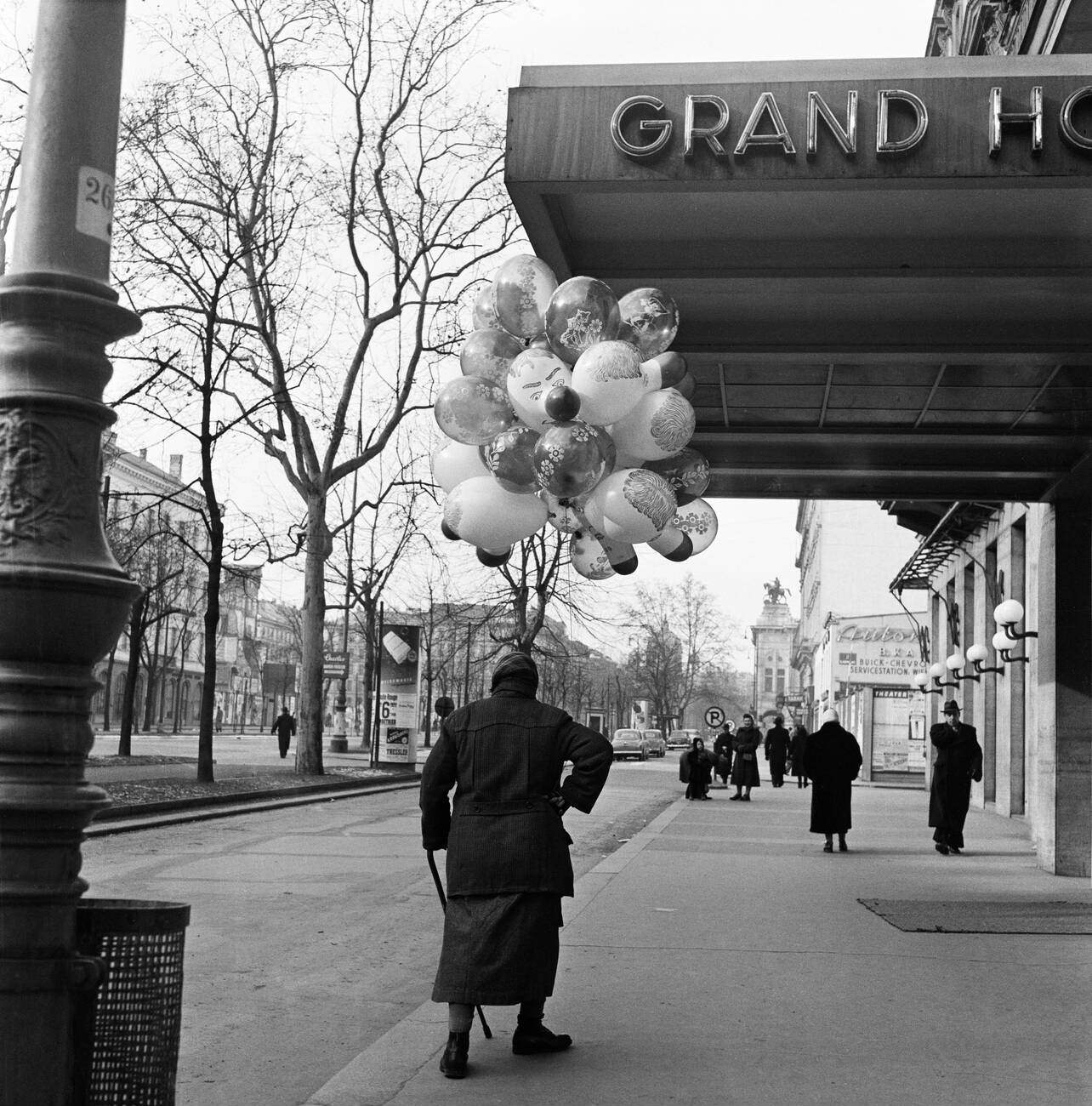 An old woman selling balloons on the cold wintry streets of Vienna. A contented customer with his purchase, February 1954.