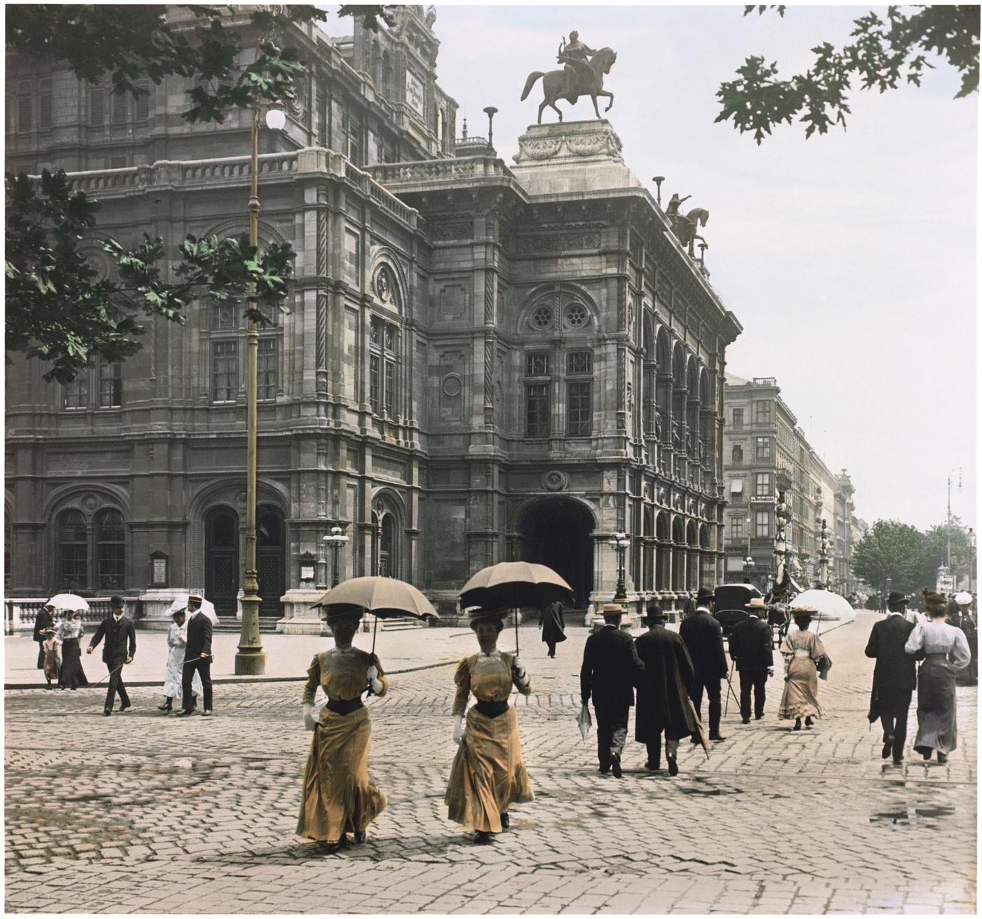 Pedestrians walking in front of the Vienna Court Opera, with statues of Erato and Harmony on winged horses. Vienna, Austria, 1907.