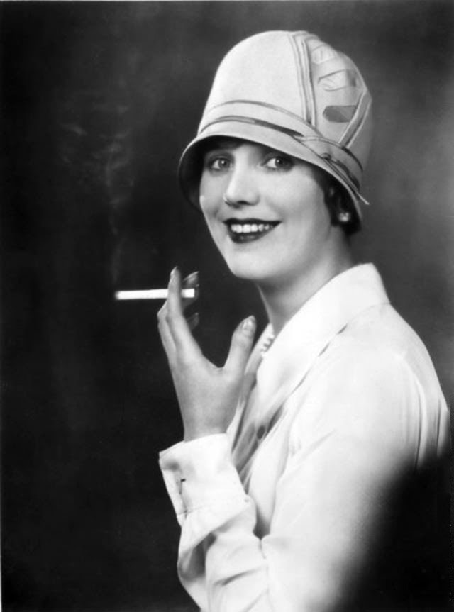Enid Stamp-Taylor smoking a cigarette while wearing a cloche hat designed by Lincoln Bennett, 1927.