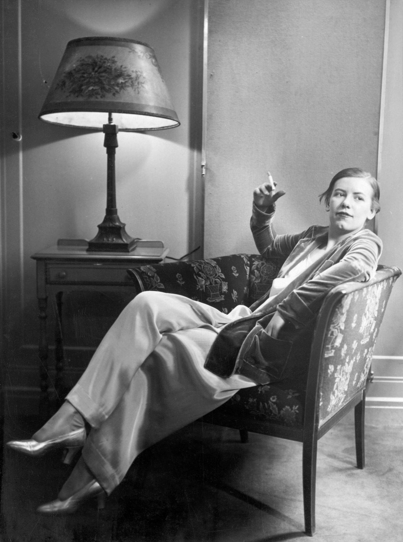 Woman Lounges in Rose Pink Pajamas, 1928: A Chic and Relaxing Moment with a Cigarette