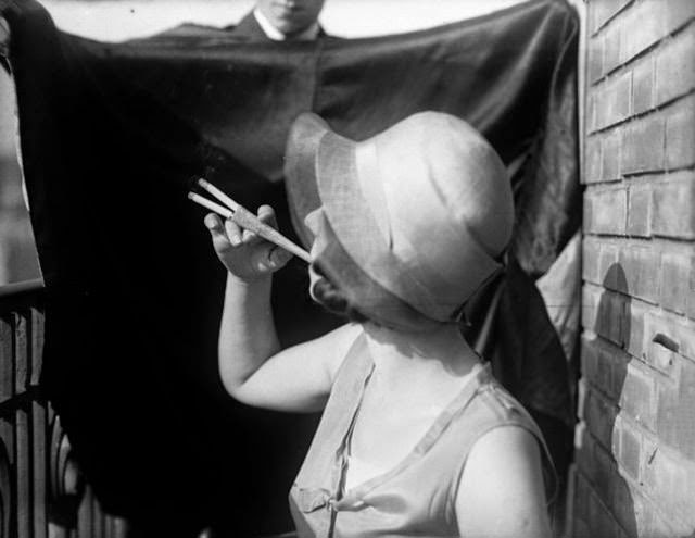 A woman smoking two cigarettes simultaneously with an elegant cocktail cigaratte holder, 1929