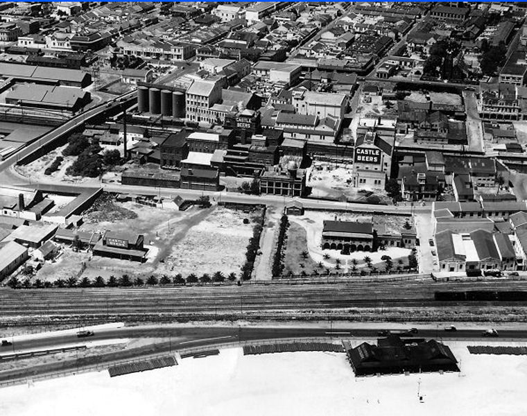 Woodstock Beach, 1935. Before moving to Newlands in 1955 the Castle Brewery was located in lower Woodstock. The road on the left crossing the railway lines is Lower Church street that is still used today.