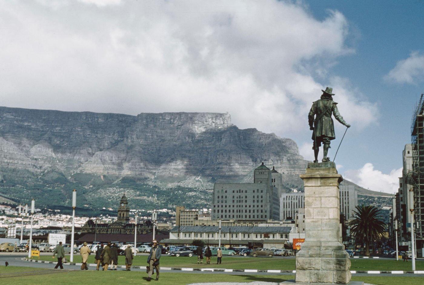 Pedestrians walk past the statue of Jan van Riebeeck at the end of Adderley Street, with Table Mountain in the background, in the center of the city of Cape Town, 1960