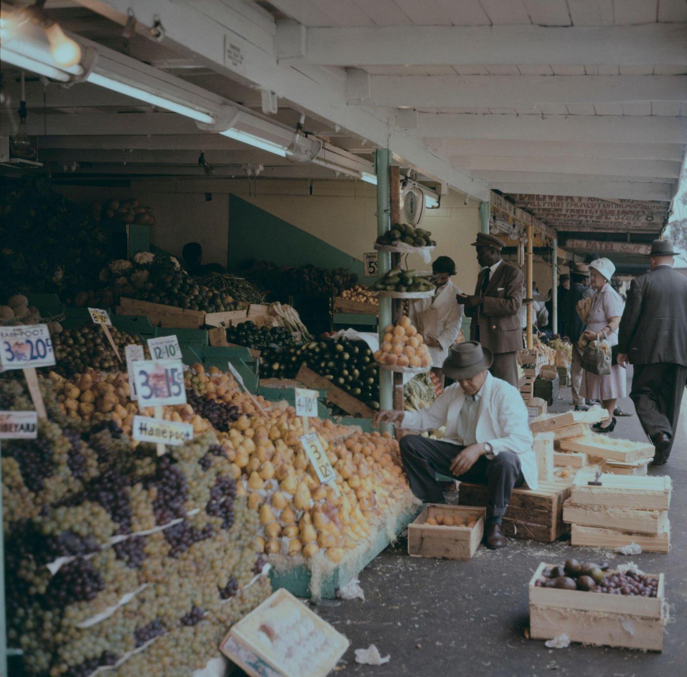 Customers are served by a stallholder at a fruit market near City Hall in the center of the city of Cape Town, 1965