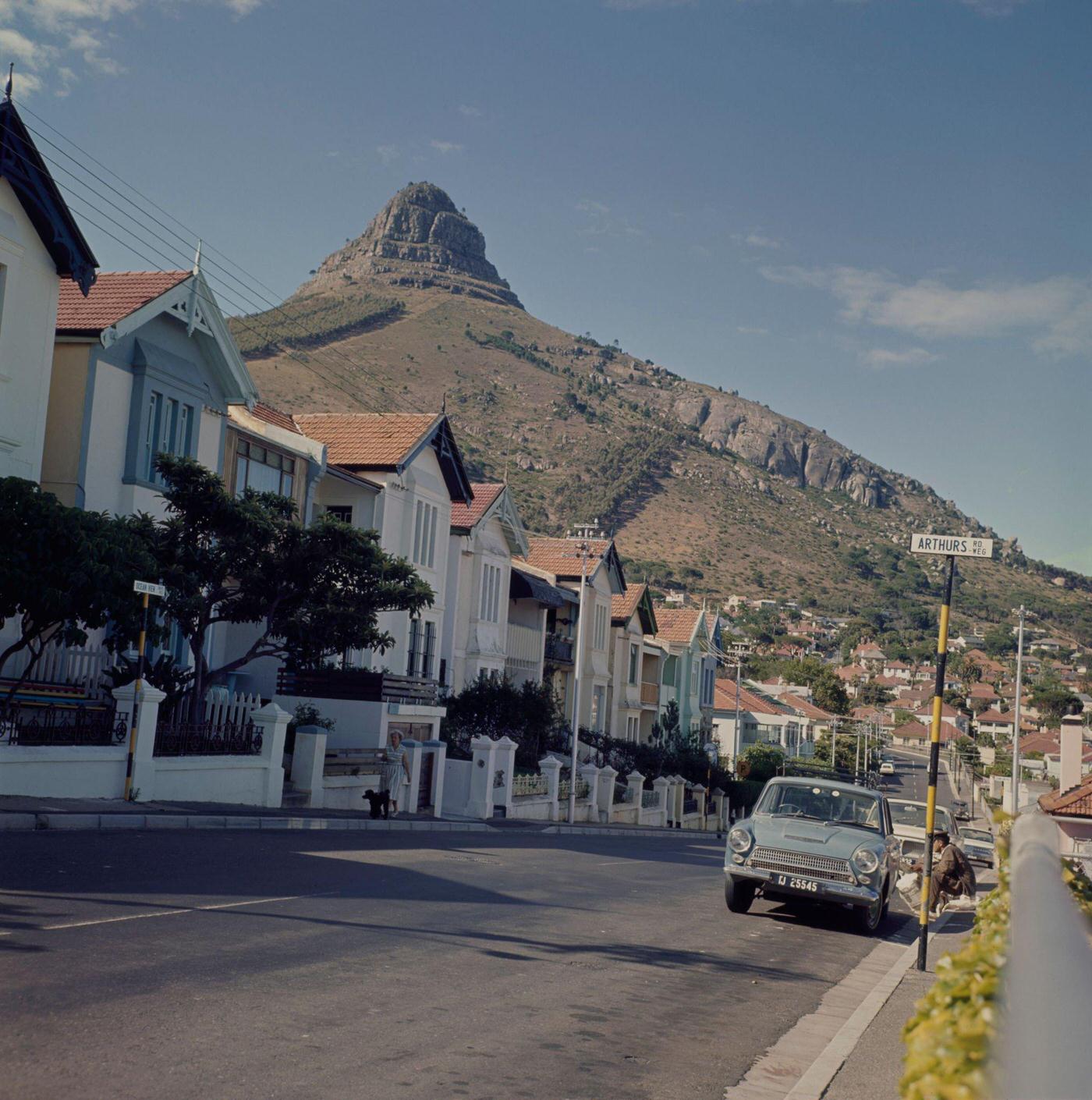 A pedestrian walks past cars parked on Arthurs Road in the Seapoint district of the city of Cape Town in Cape Province (later Western Cape) in South Africa in 1966.