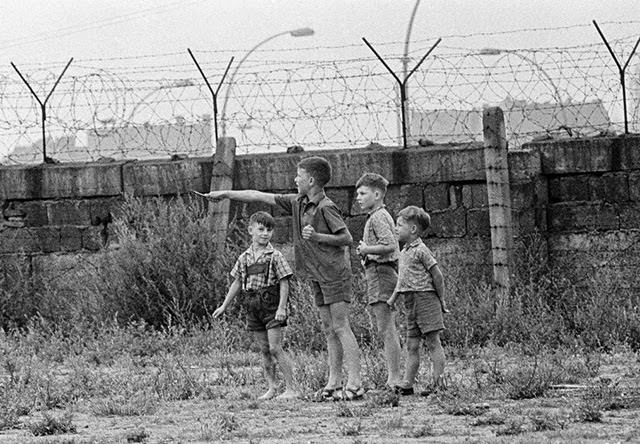 Young boys playing near a barbed wire fence along the border between East and West Berlin.