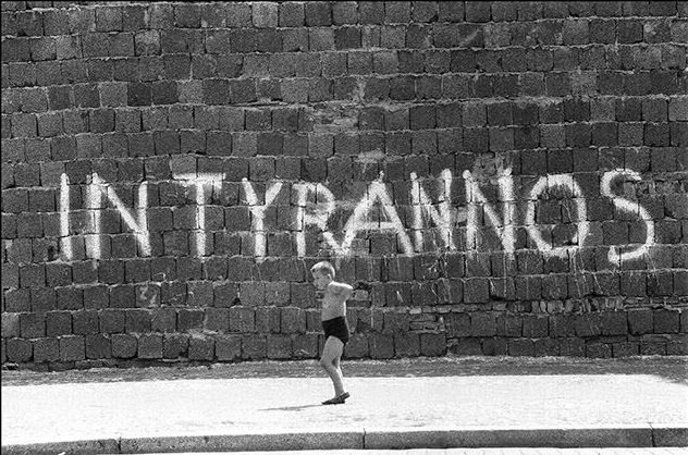 A child playing by the Berlin Wall. The latin words "IN TYRANNOS" has been written in capital letters on the Wall. West-Berlin.