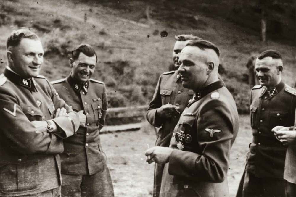 Taking a break. The second person is the notorious concentration camp doctor Josef Mengele (The Angel of the Death).