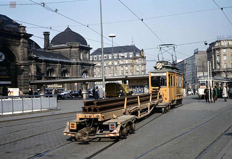 Frankfurt 4-wheel Arbeitswagen (works tram) 2040 passing the tram stops in front of Frankfurt Hauptbahnhof. The trailer wagon is carrying six lengths of new tram rail, March 30, 1967