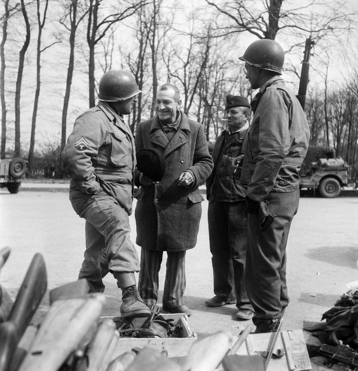 French prisoner commander Bellon chats with American soldiers in front of a pile of weapons belonging to the SS at Buchenwald Nazi camp, April 12, 1945.