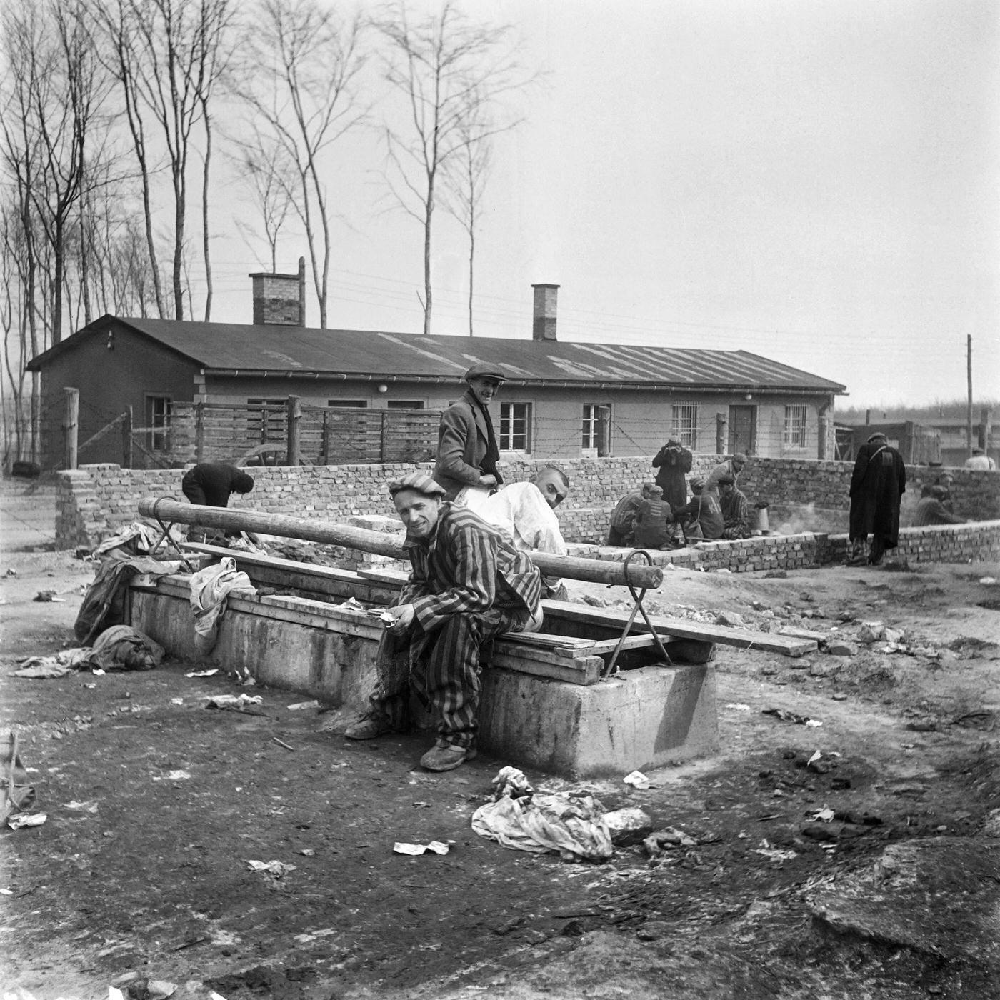 Survivors of Buchenwald concentration camp sitting on a latrine after its liberation by Allied troops in April 1945.