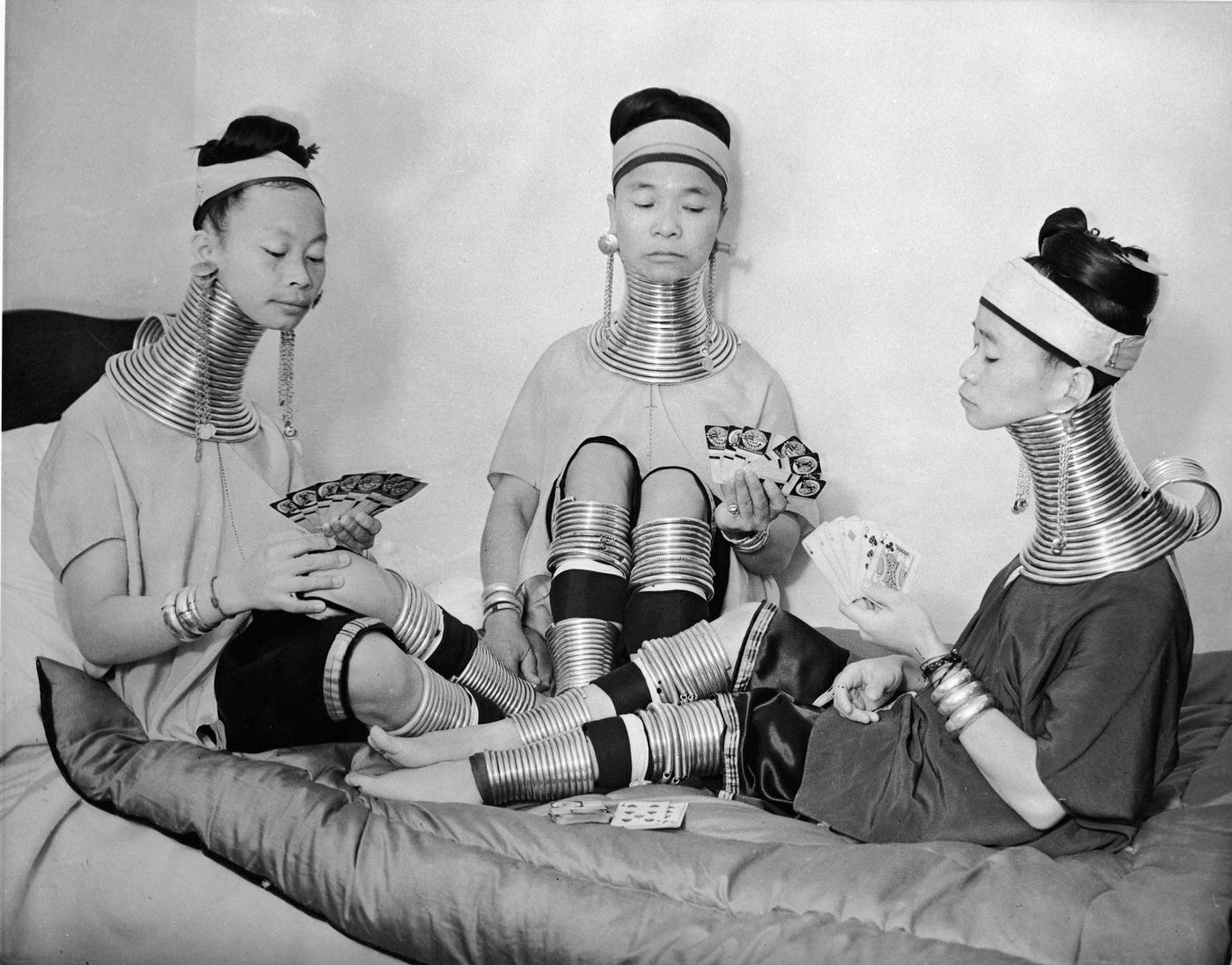 Three Burmese women from a circus playing cards while wearing brass neck and leg rings, London, 1935.