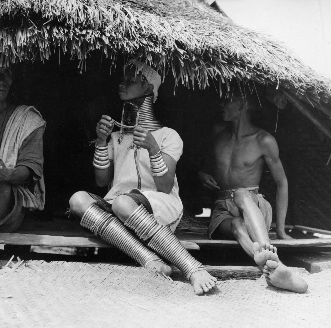Group of Padaung, or Kayan people, sitting in a hut, Burma, 1950.