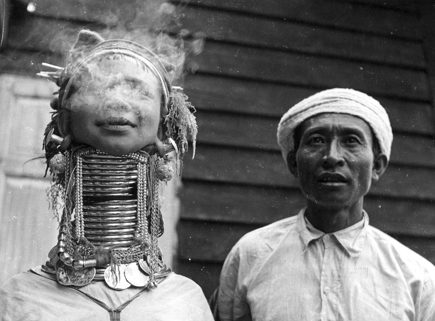 Padaung woman exhaling smoke, known for brass rings fitted to their necks and limbs, Burma, 1955.