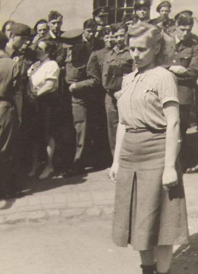 A woman is marched before gathered crowds during the war crimes trial held after the liberation of the Bergen-Belsen death camp.