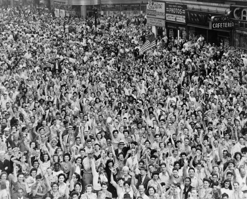 Crowd of people, many waving, in Times Square on V-J Day at time of announcement of the Japanese surrender in 1945.