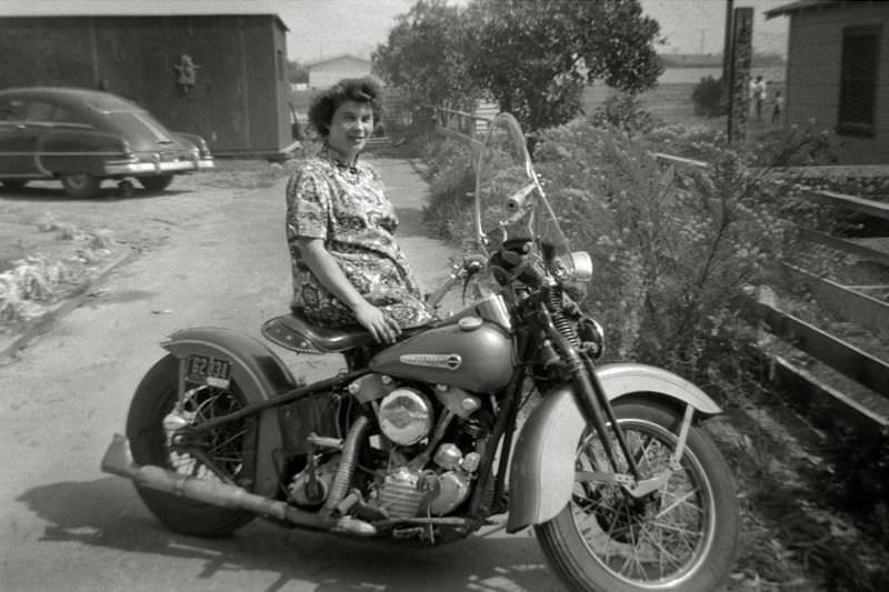 Young mother posing with the family Harley-Davidson in California, 1953