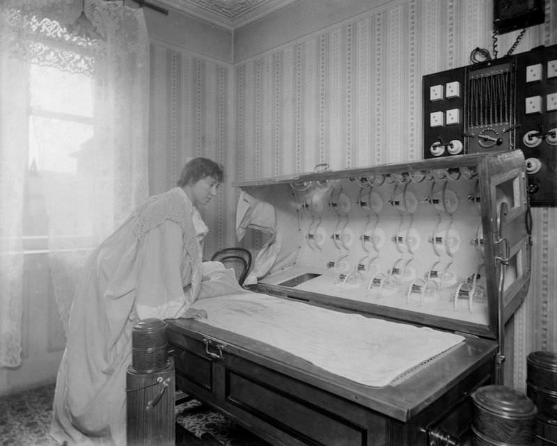 A woman inspects an Electric Bath at the Light Care Institute. The Electric Bath is probably a forerunner of the modern sunbed, although it was more likely used for medicinal reasons, circa 1900.