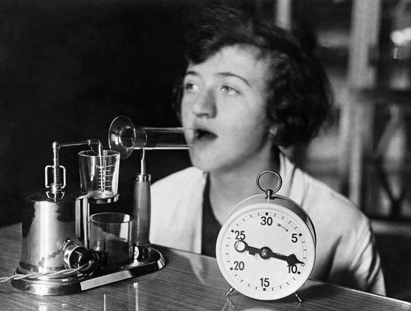 A woman using an electric inhaling apparatus which produces a medicated fog used in the treatment of colds and influenza, circa 1929.