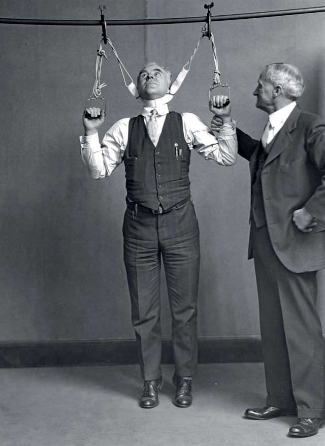 Post Office Department Inspector DF Angier (left) and Dr. LF Kebler, formerly of the Food and Drug Administration, try out a stretching device which claimed to increase height by 2 to 6 inches, 1931.