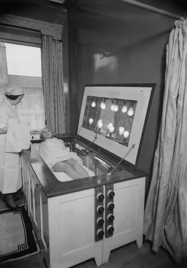 A nurse handing a towel to a woman on a sunbed, 1934.