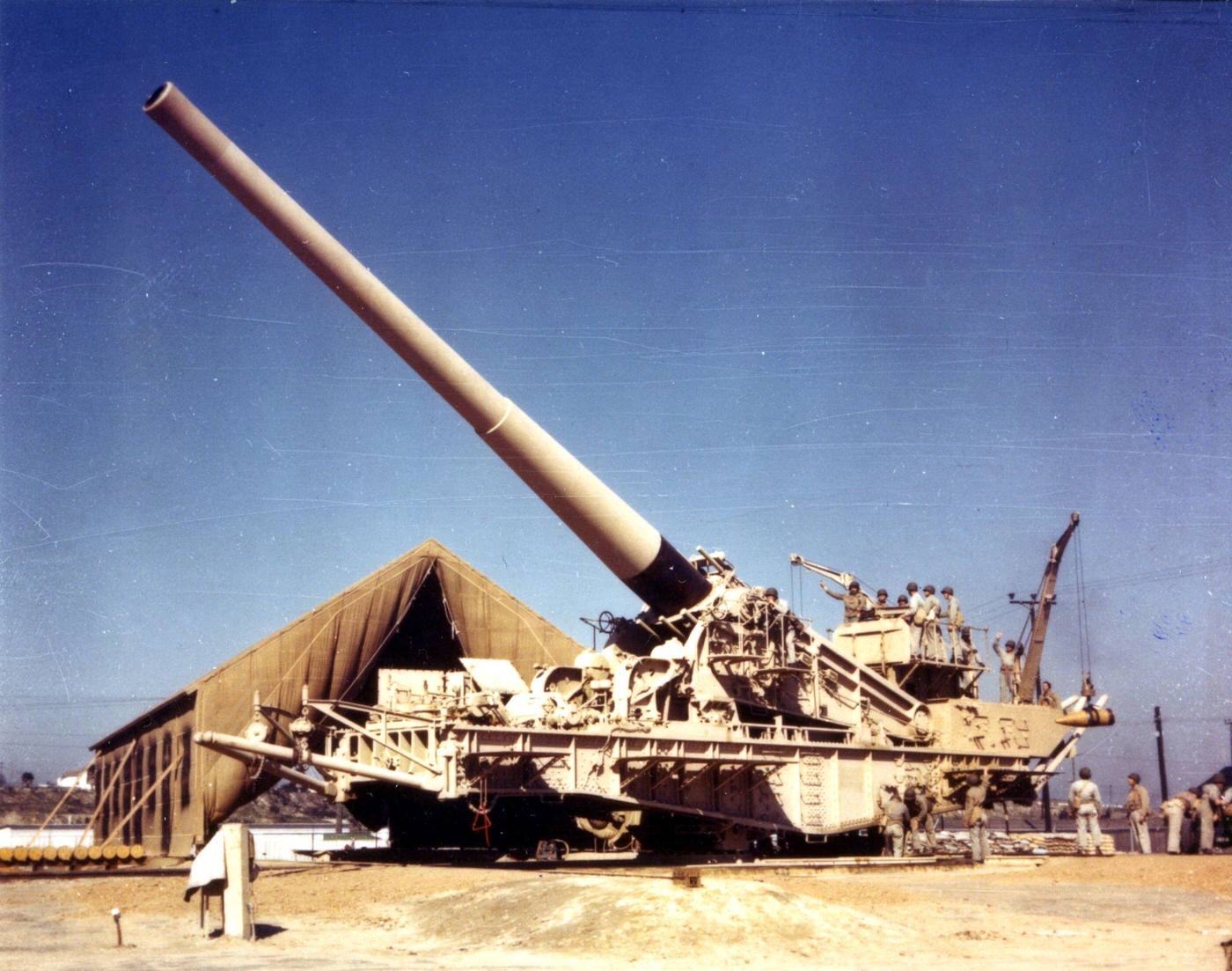 Massive railroad gun towering over troops, 1940s.