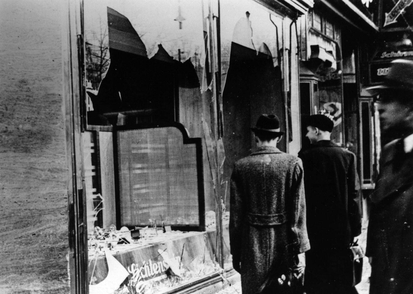 Onlookers at a smashed Jewish shop window in Berlin after Kristallnacht, November 1938.