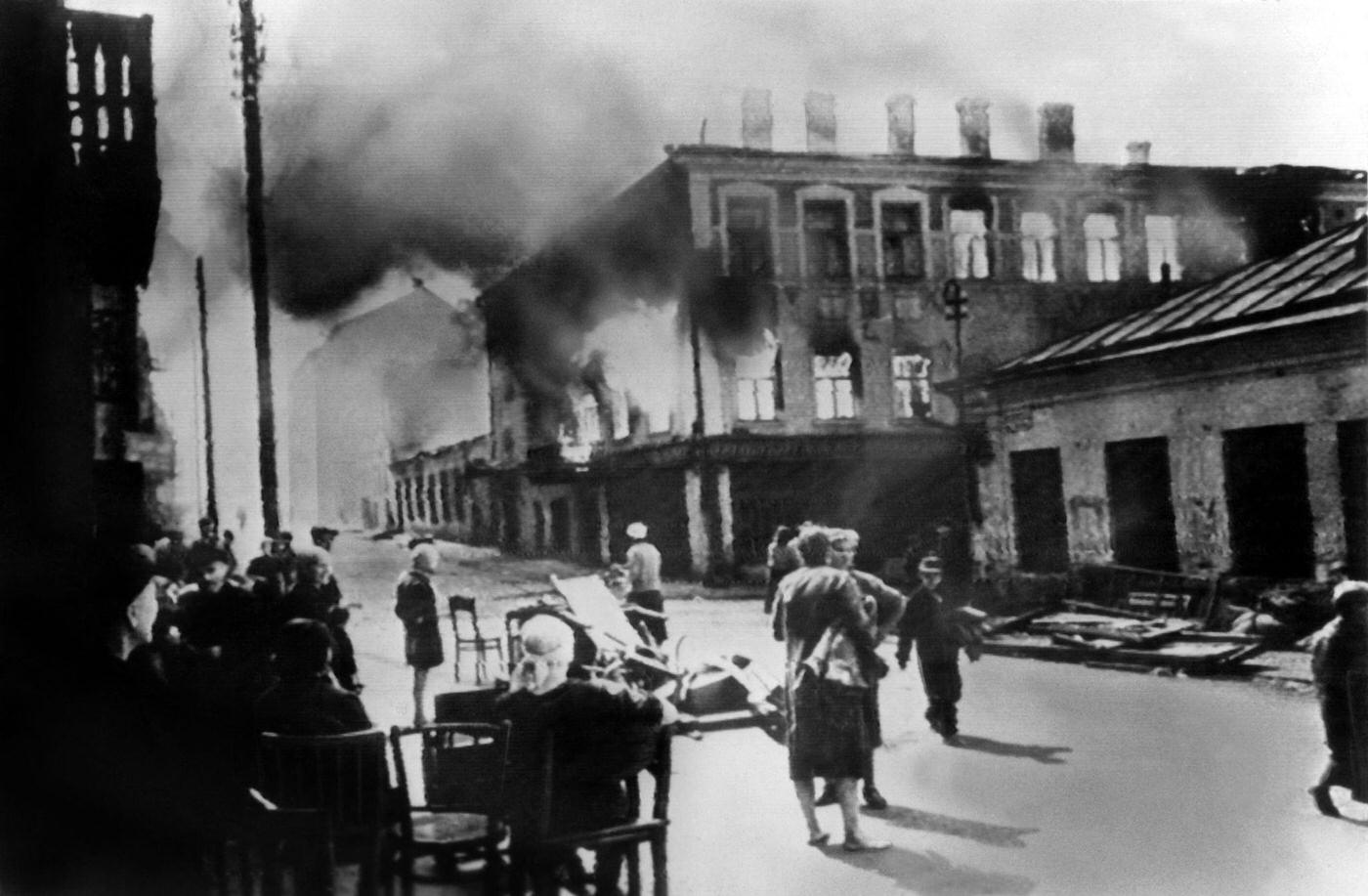 Russian civilians watch the destruction of a building fired by the Nazis in Minsk, Soviet Union, July 1944.