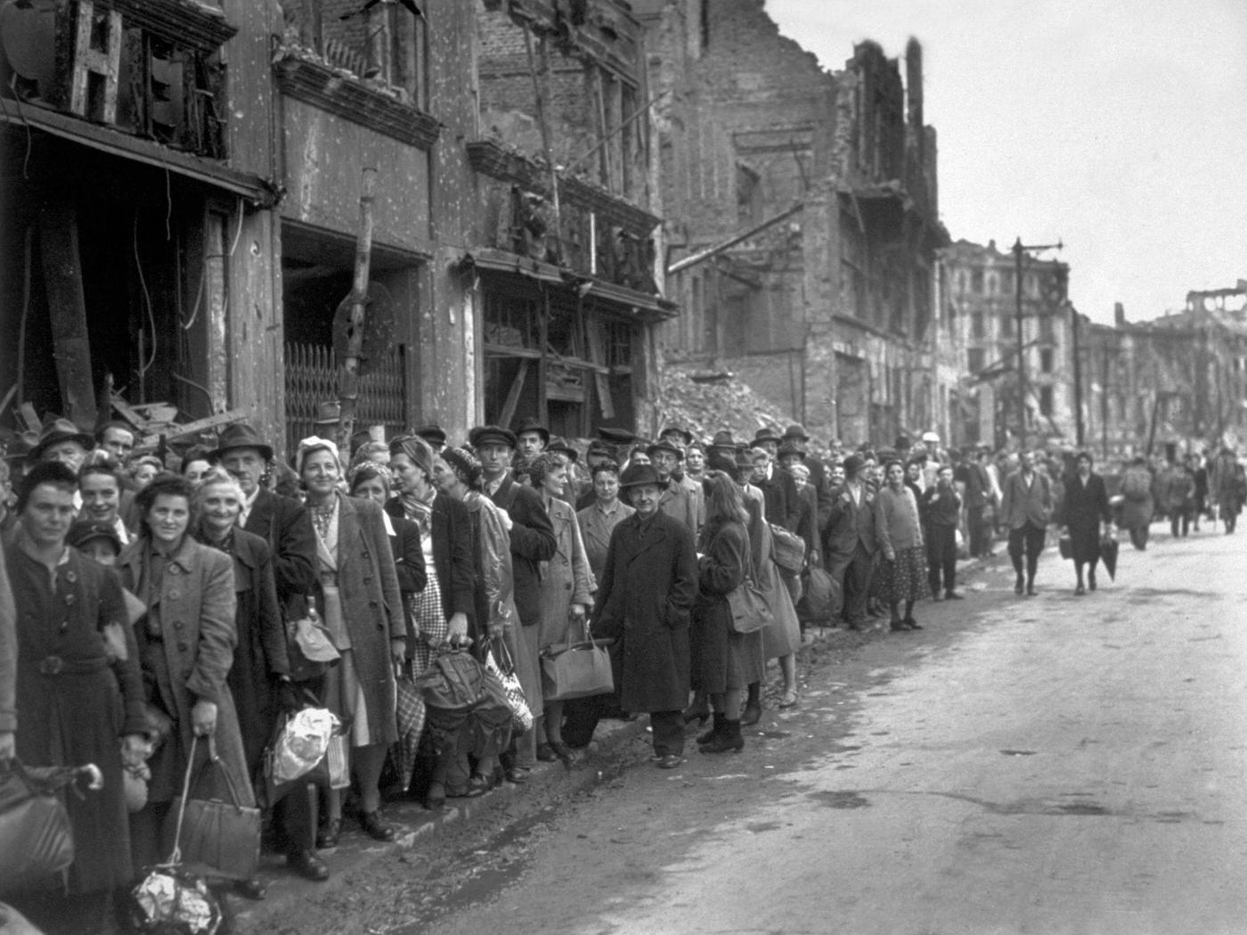 Bus queue in a bomb-damaged street in Berlin, circa 1945.