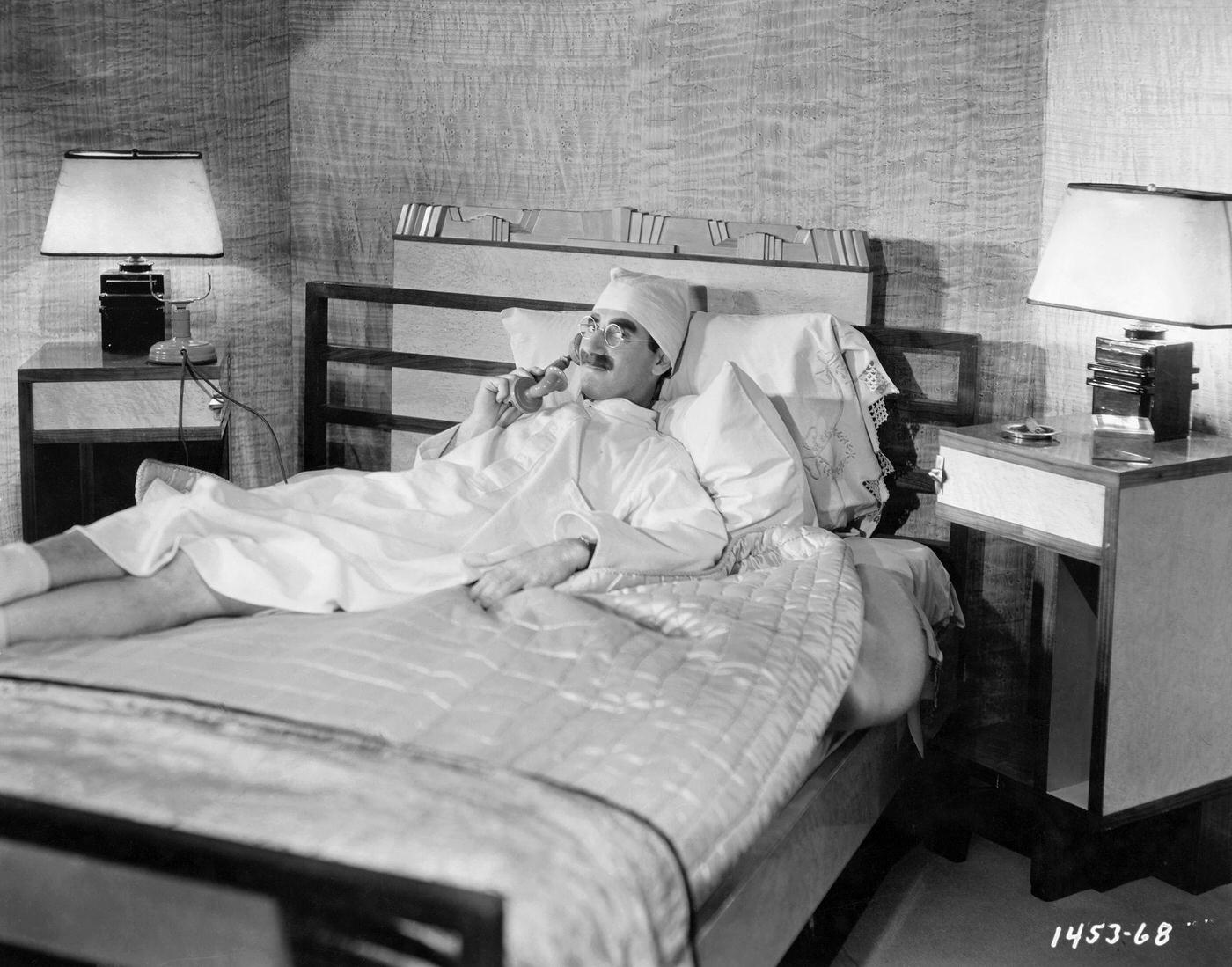Groucho Marx lounging on a bed, talking on the phone for the film Duck Soup (1933).