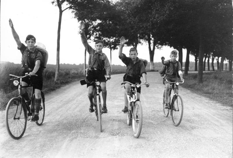 Members of Hitler Youth giving the Nazi Party salute on their bicycles, near Berlin, Germany, 1932.