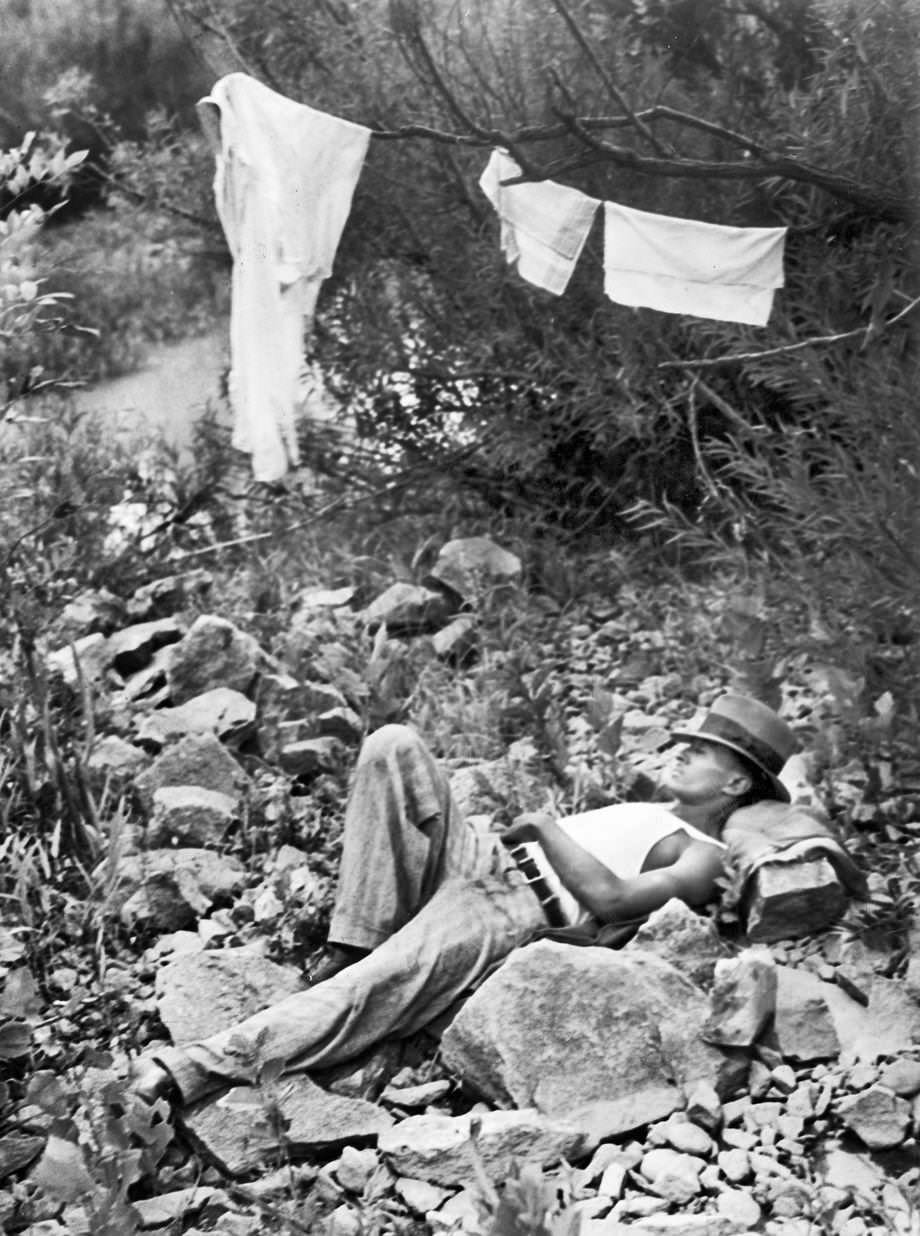 A man napped on Cherry Isle in the James River in Richmond while his clothes and belongings dried on a line, 1937.