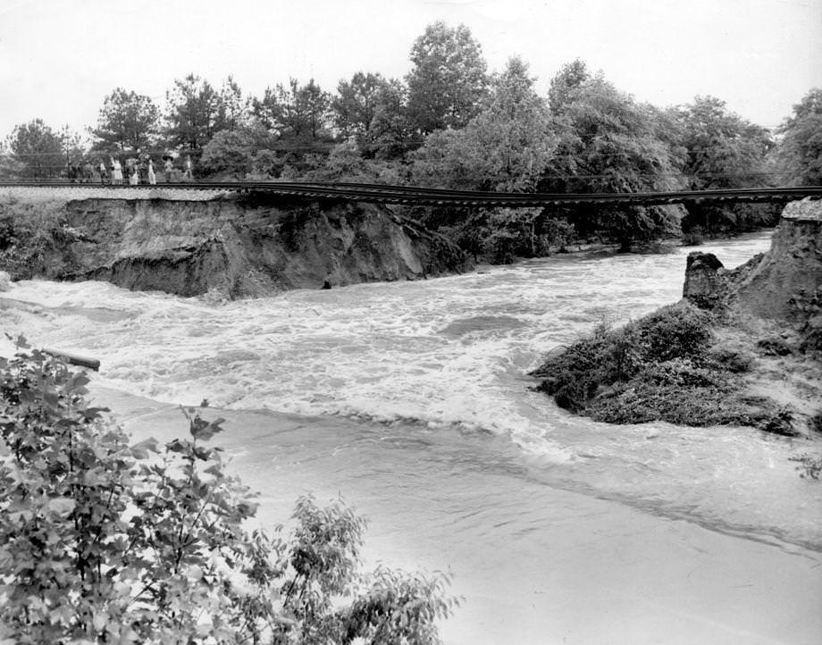 Flooding from heavy rains in the Windsor Shades area of New Kent County washed out a Chesapeake & Ohio Railway bed, leaving unsupported rails spanning a chasm, 1948.