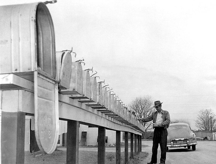Postman Sam H. Mellichampe delivered mail in a long line of boxes at a trailer park near Petersburg. He said the row of mailboxes was the longest on his route, 1959.
