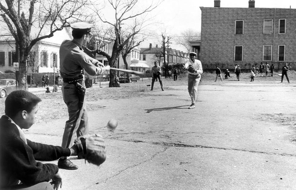 Richmond police officer Glenwood W. Burley took a moment away from his patrol work to play baseball with youths in the Fulton neighborhood, 1967.