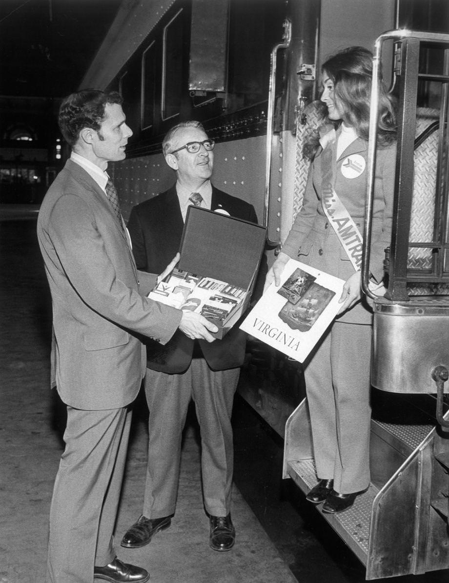 As Amtrak consolidated passenger rail service in America, E.M.C. Quincy (left) of the Greater Richmond Chamber of Commerce presented a gift of Richmond tobacco products and a record about Virginia to Amtrak’s Teresa Cunningham at Main Street Station in downtown Richmond, 1971.