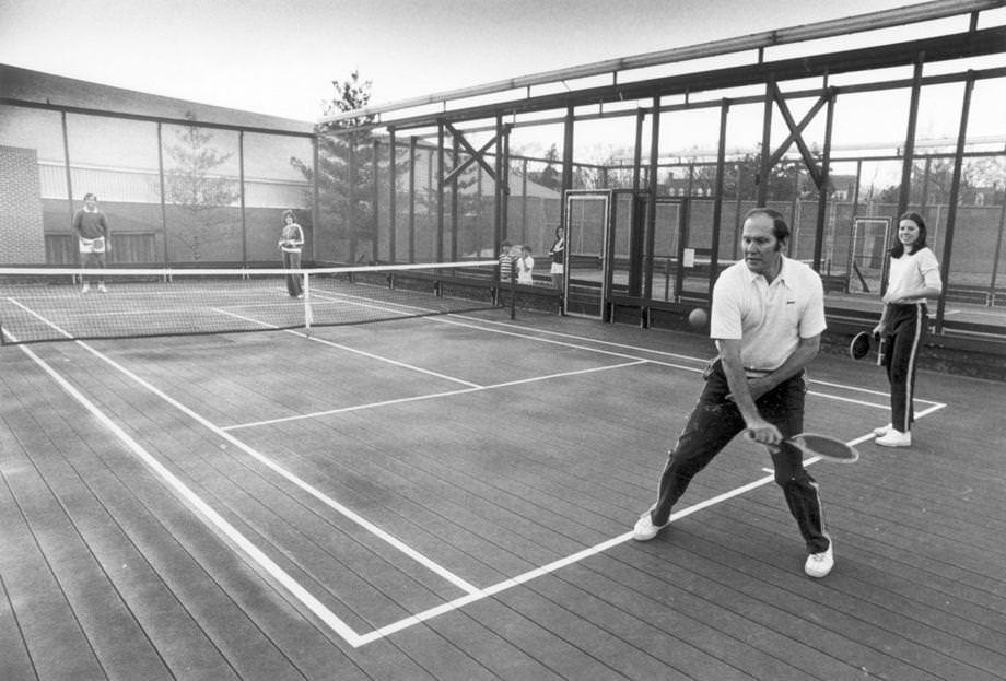 Hal Burrows serves while partner Courtney Drake looks on at CCV's platform tennis facility, 1978