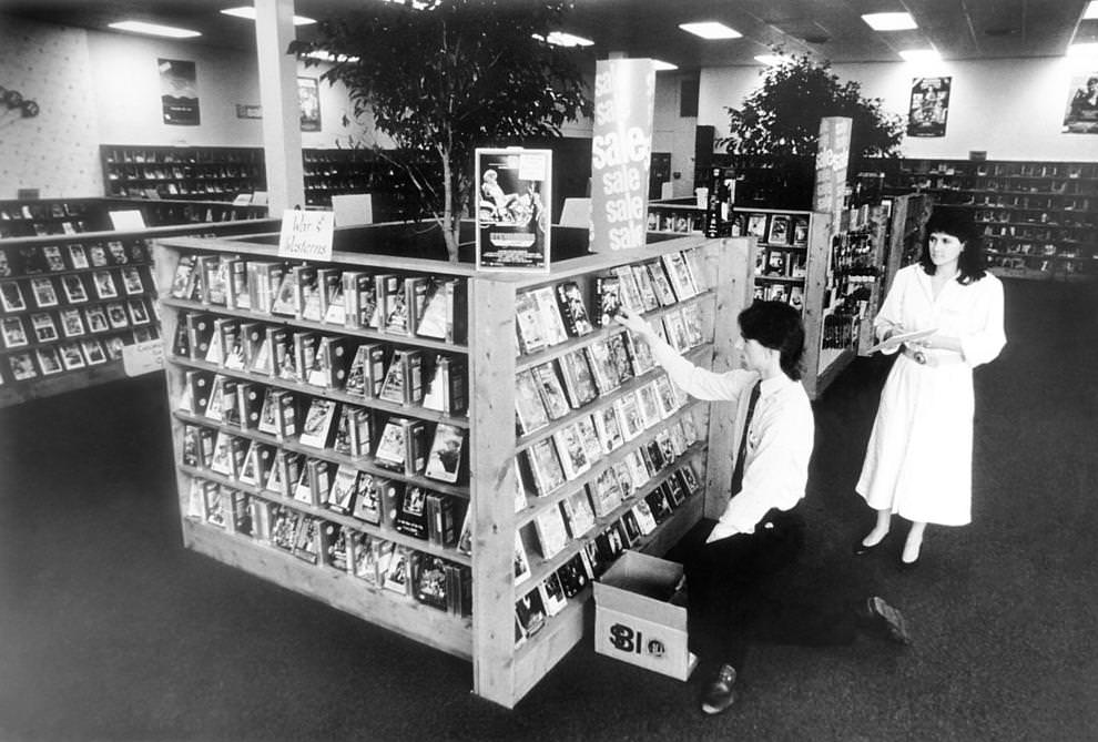 Manager Cissy Travers (right) and assistant John Gurski organized the shelves at Video World, a video rental store on Robious Road in Chesterfield County, 1987