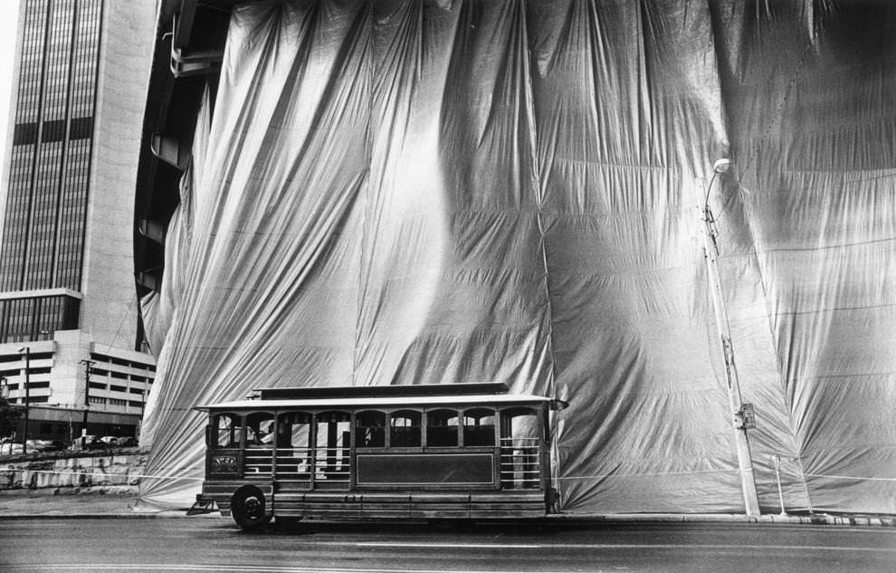 A trolley passed by a large screen that protected passing vehicles from sandblasting and painting under Interstate 95 on East Main Street, 1988