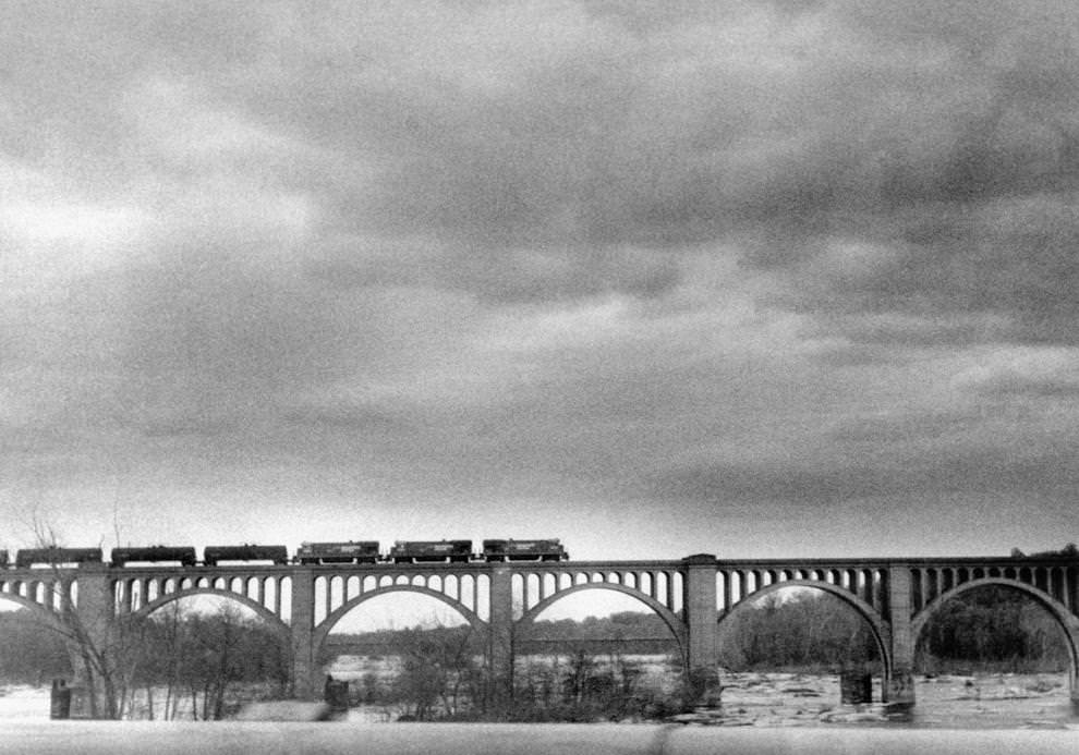 Under dark skies, a freight train made a southbound crossing of the James River on the Seaboard System Railroad bridge downriver from the Powhite Parkway, 1986