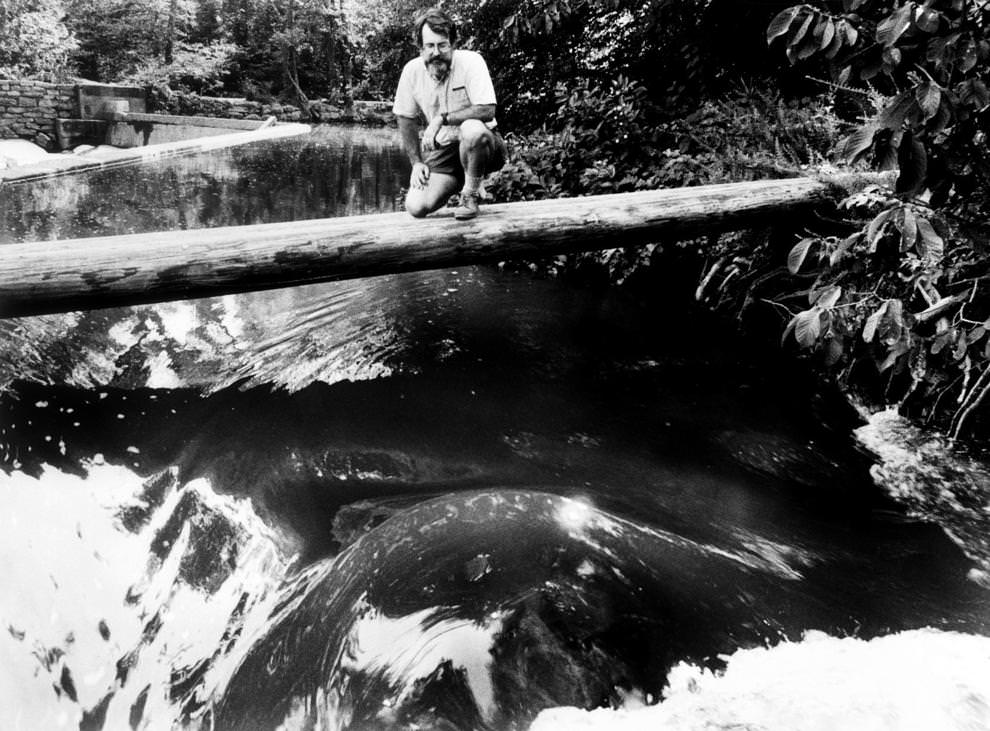 The James River Park System’s Ralph R. White knelt on a log above the river, 1989.